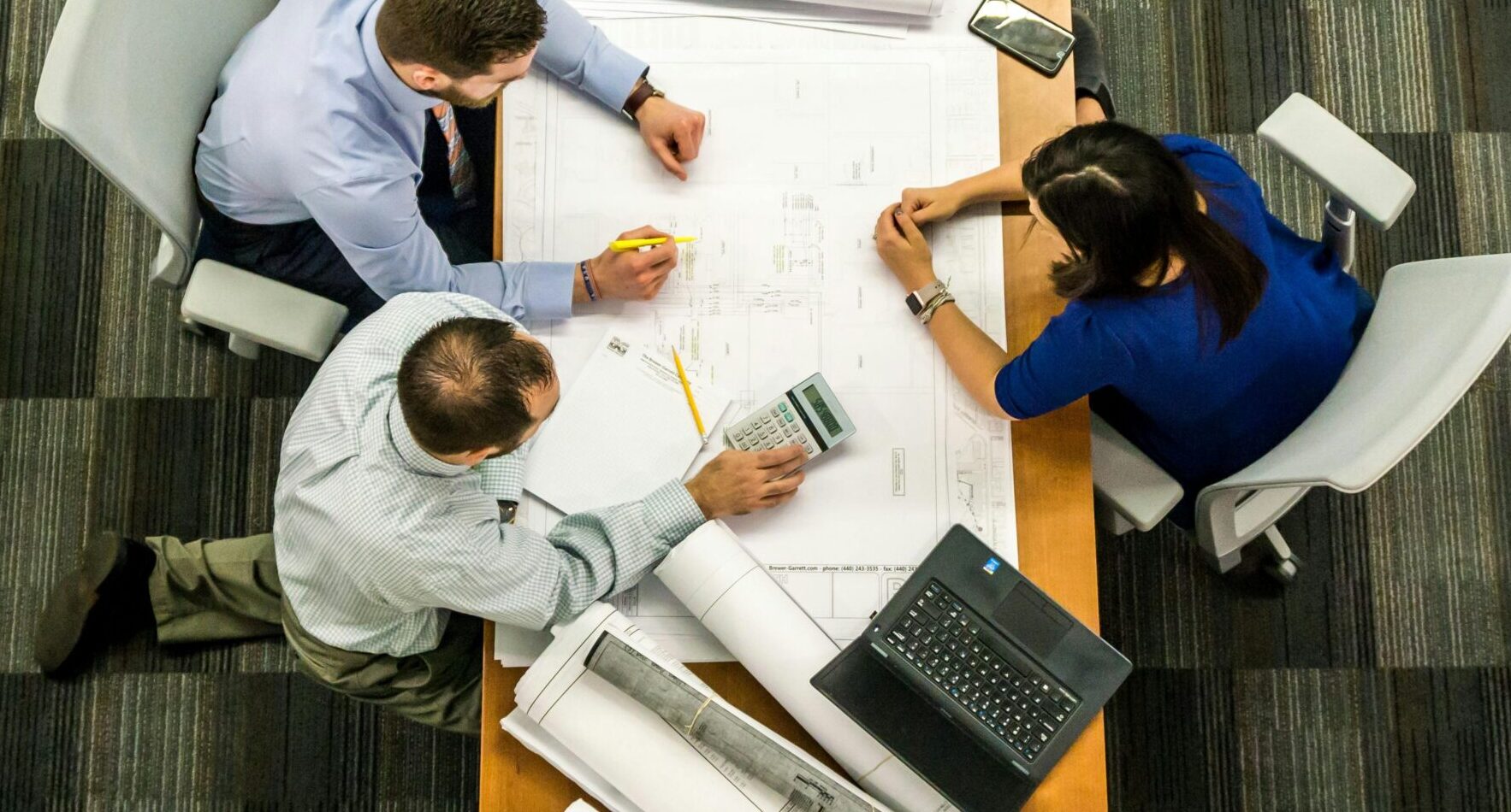 Top view of a team working on construction plans in an office setting.